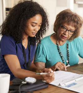 Nurse filling out chart with an older woman.