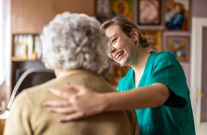 edited A smiling in-home nurse helping an elderly woman with her back to the camera.