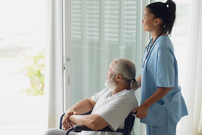 Man sitting in wheel chair with healthcare provide behind him