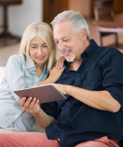 Couple sitting on a couch and looking at a tablet